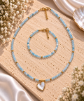 Parure collier et bracelet en perles facettées bleu ciel d'aigue-marine et billes dorées avec pendentif cœur nacré serti doré