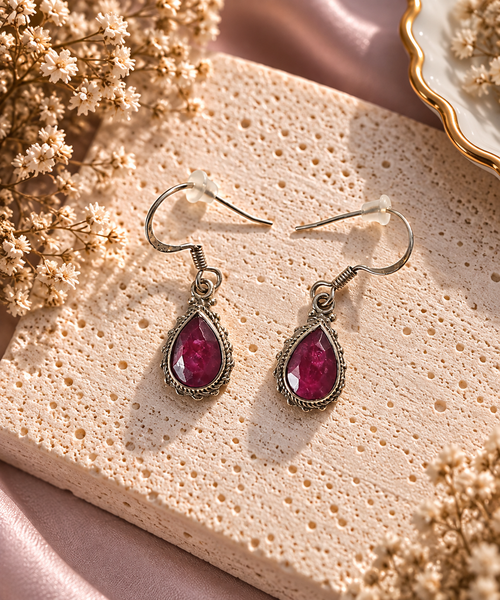Boucles d'oreilles pendantes cabochons larme facettee de corindon rouge rubis intense serties dans un cadre argent torsade aux details ciseles