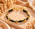 Bracelet Nocturne à maillons dorés allongés entrelacés d’une bande noire, avec fermoir mousqueton et chaînette d’extension
